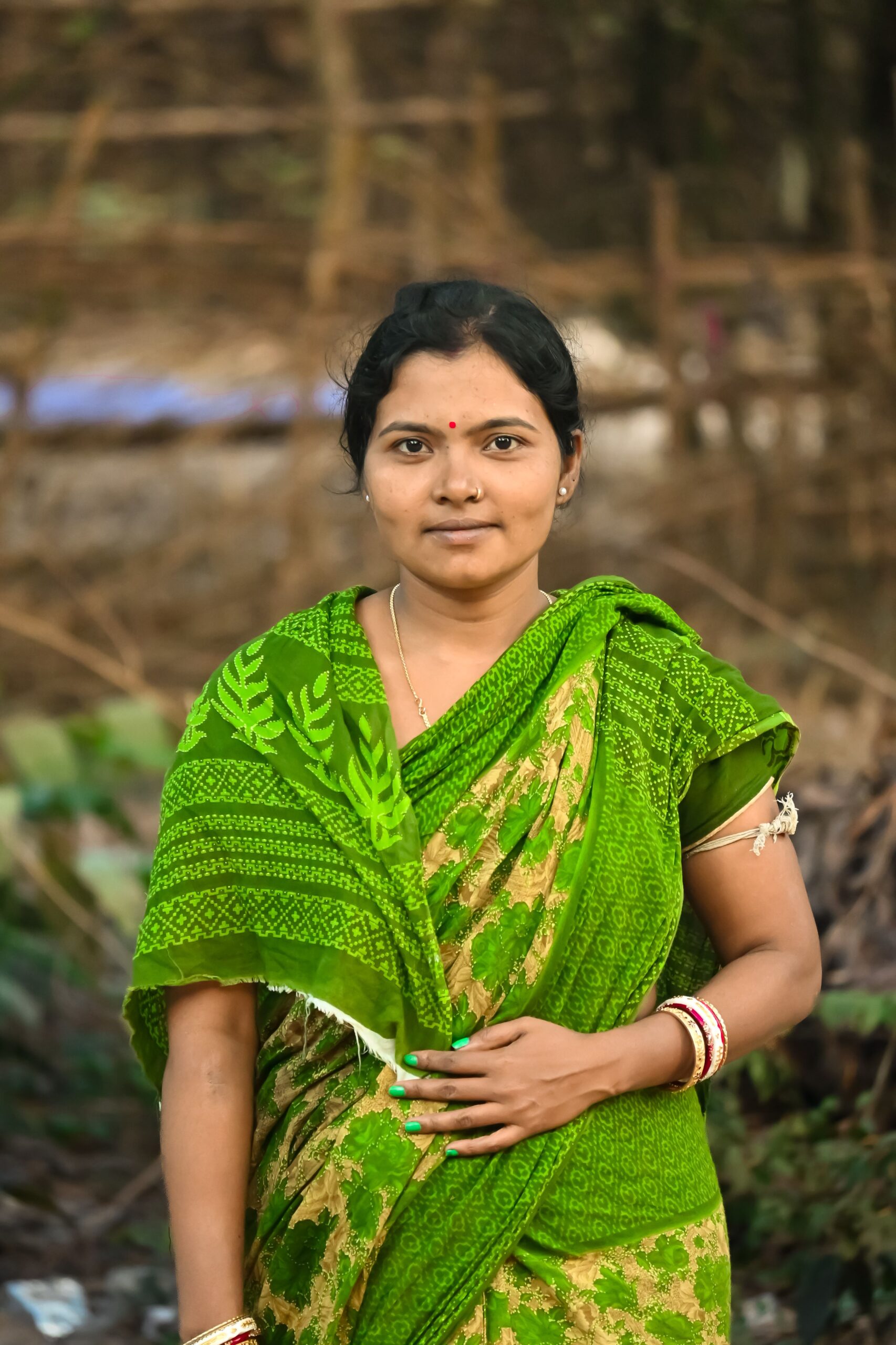 A woman in vibrant green sari posing outdoors in India.